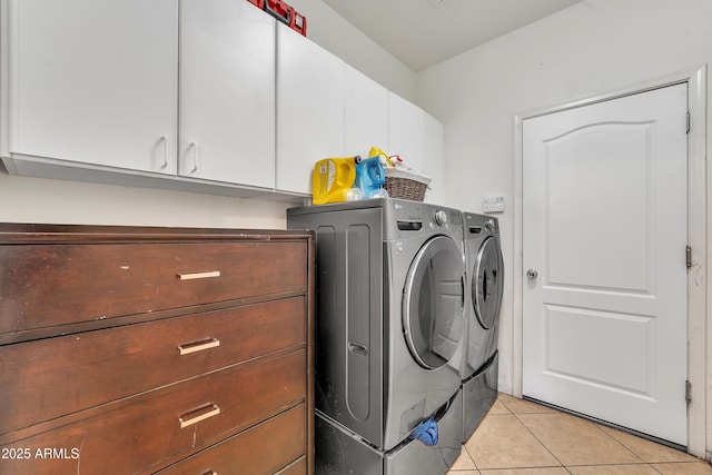 washroom with cabinet space, light tile patterned floors, and washing machine and clothes dryer