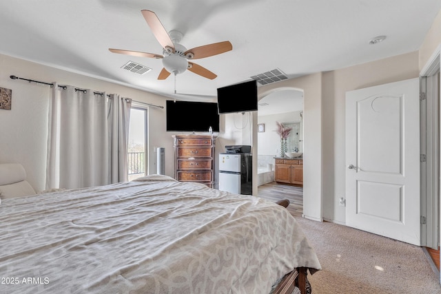 bedroom featuring light colored carpet, freestanding refrigerator, visible vents, and arched walkways