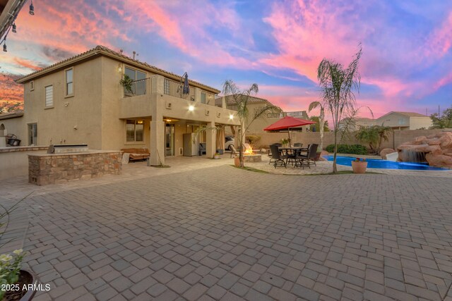 back of property with a patio, a balcony, fence, exterior kitchen, and stucco siding
