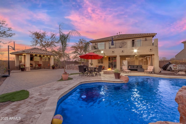 outdoor pool with an outdoor living space with a fire pit, a patio, a gazebo, and fence