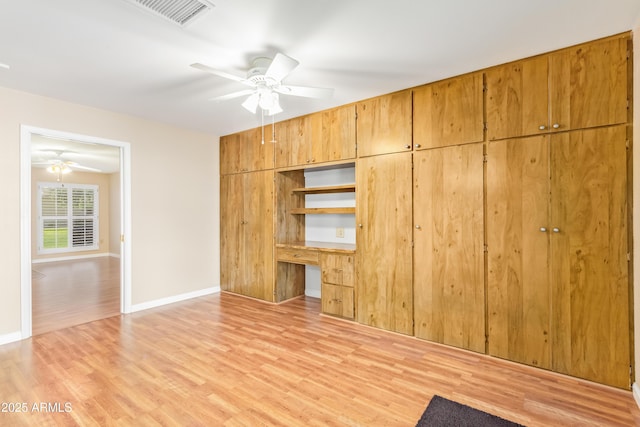 unfurnished bedroom featuring ceiling fan, built in desk, a closet, and light hardwood / wood-style flooring