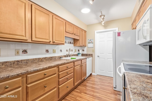 kitchen with white appliances, light hardwood / wood-style floors, sink, and decorative backsplash