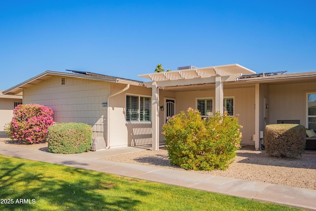 view of front of property featuring a pergola and solar panels