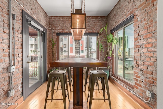 dining room with light wood-style flooring and brick wall