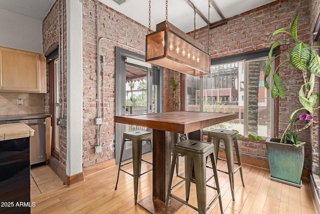dining area featuring light wood-style floors and brick wall