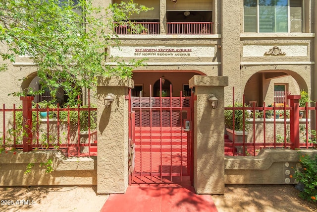 exterior space featuring fence, a gate, and stucco siding