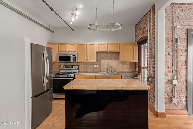 kitchen with tile countertops, light brown cabinetry, tasteful backsplash, a sink, and stainless steel appliances