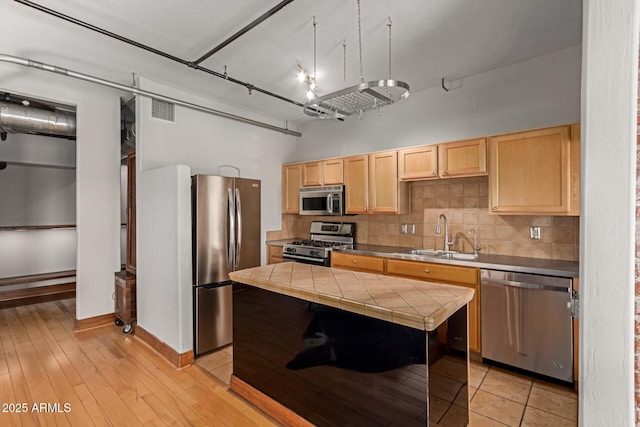 kitchen featuring decorative backsplash, visible vents, light brown cabinetry, a sink, and stainless steel appliances