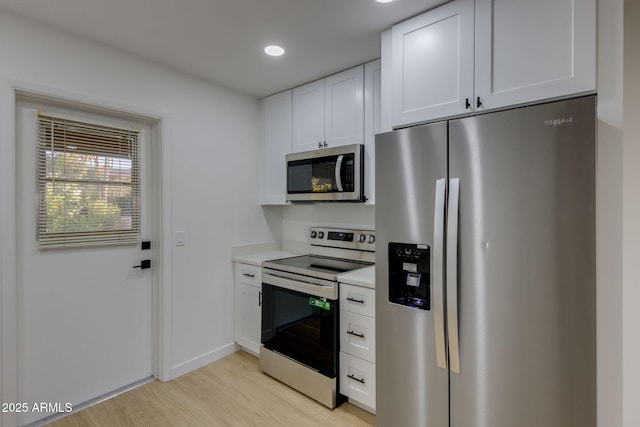 kitchen featuring stainless steel appliances, light wood finished floors, white cabinets, light countertops, and baseboards