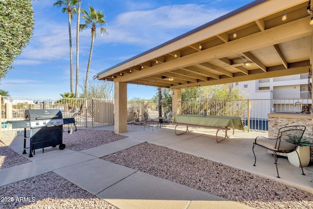 view of patio with grilling area, fence, and a sink