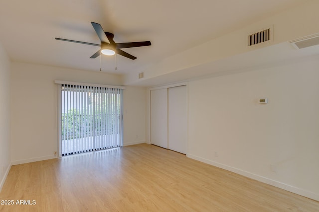 empty room with light wood-style floors, a ceiling fan, and baseboards