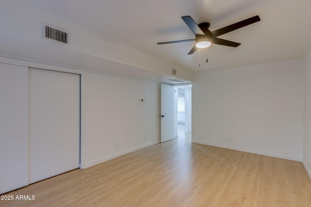 unfurnished bedroom featuring light wood finished floors, a closet, baseboards, and a ceiling fan