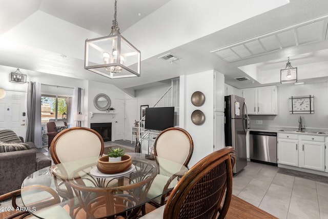 dining space with light tile patterned floors, visible vents, a tray ceiling, and a glass covered fireplace