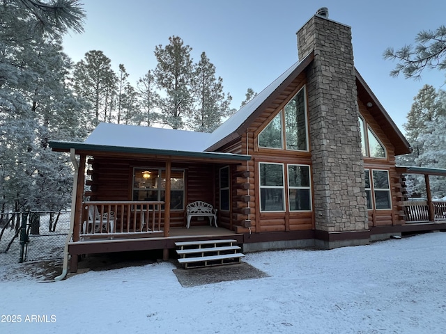 2793 Canyon Ridge Rd, Overgaard, AZ 85933 - snow covered property featuring a chimney, fence, log siding, a wooden deck, and a porch