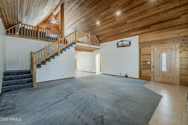 2793 Canyon Ridge Rd, Overgaard, AZ 85933 - unfurnished living room with arched walkways, a ceiling fan, stairs, wooden walls, and high vaulted ceiling