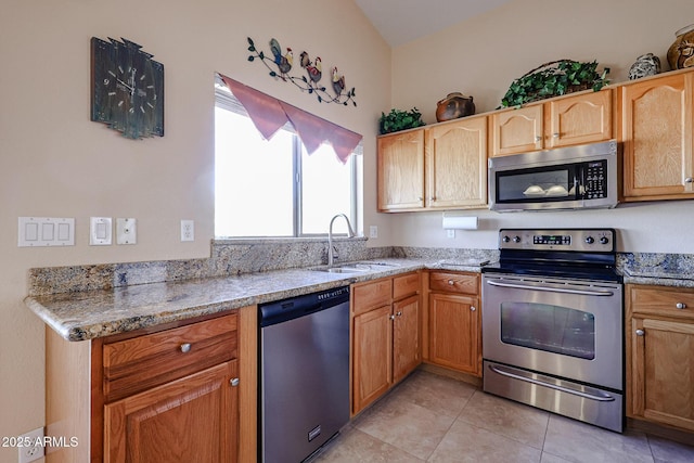 kitchen with stainless steel appliances, light tile patterned flooring, light stone countertops, and sink