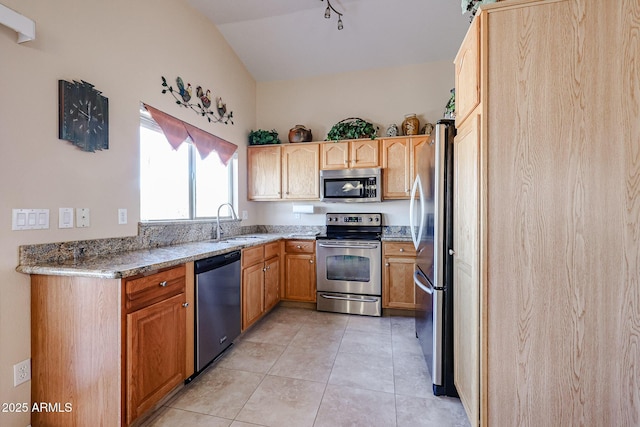 kitchen with light tile patterned floors, sink, stainless steel appliances, light stone countertops, and vaulted ceiling