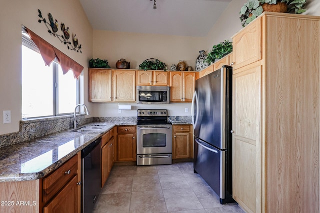 kitchen with sink, light tile patterned floors, appliances with stainless steel finishes, vaulted ceiling, and dark stone counters