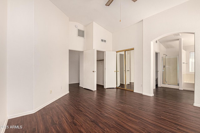 unfurnished bedroom with dark wood-style floors, visible vents, and arched walkways
