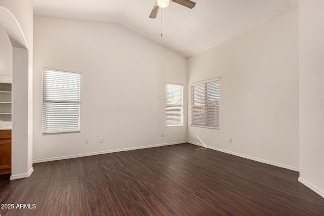 empty room featuring a ceiling fan, dark wood-style floors, baseboards, and vaulted ceiling