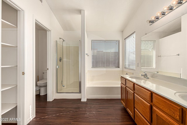 bathroom with a stall shower, toilet, a sink, wood finished floors, and a bath