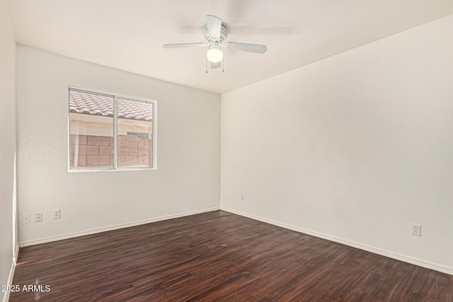 spare room featuring baseboards, dark wood-type flooring, and a ceiling fan