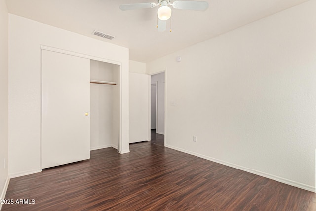unfurnished bedroom featuring a closet, visible vents, baseboards, ceiling fan, and dark wood finished floors
