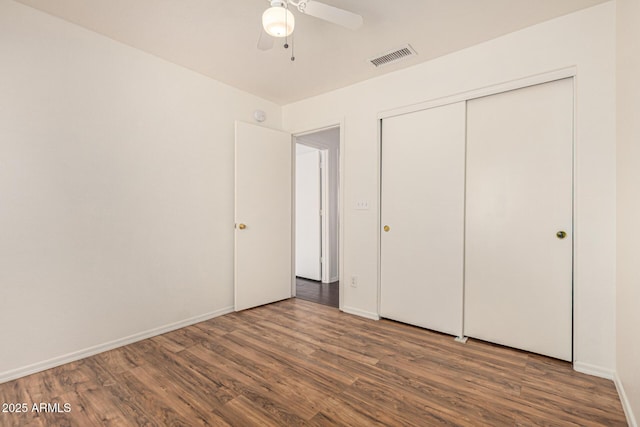 unfurnished bedroom featuring a closet, visible vents, baseboards, wood finished floors, and a ceiling fan
