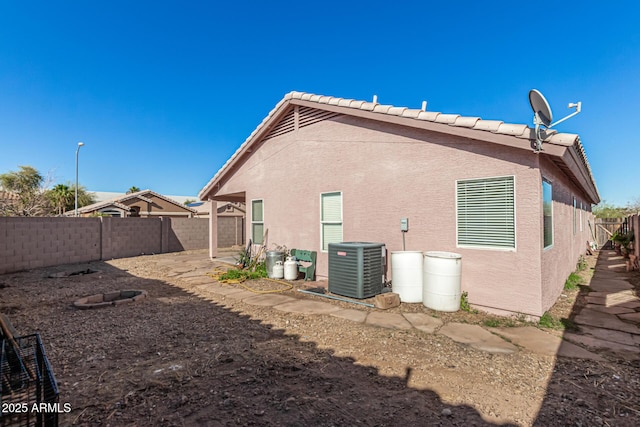 rear view of house featuring central air condition unit, stucco siding, and a fenced backyard