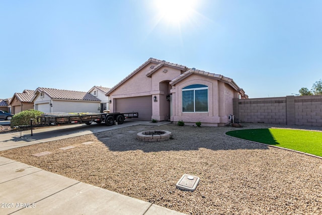 mediterranean / spanish home featuring driveway, fence, an attached garage, a tile roof, and stucco siding
