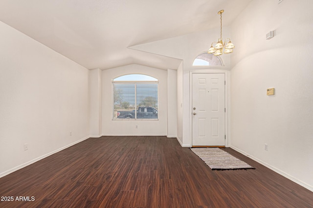 entryway featuring baseboards, dark wood-style floors, vaulted ceiling, and a chandelier