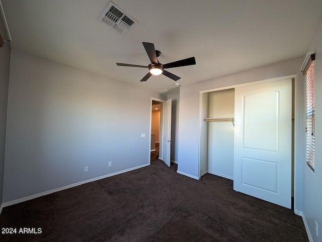 unfurnished bedroom featuring dark carpet, a closet, and ceiling fan