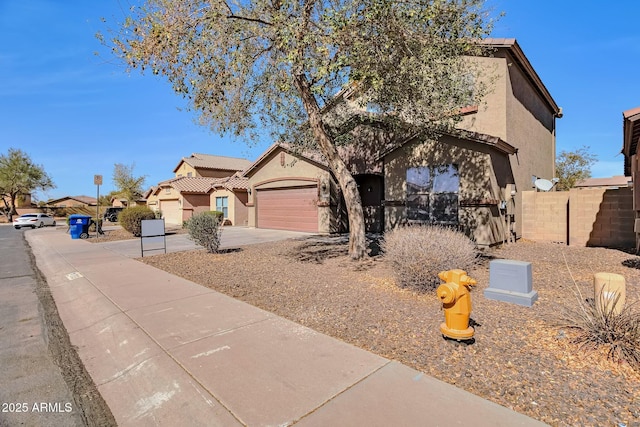 view of front of home with concrete driveway, fence, an attached garage, and stucco siding