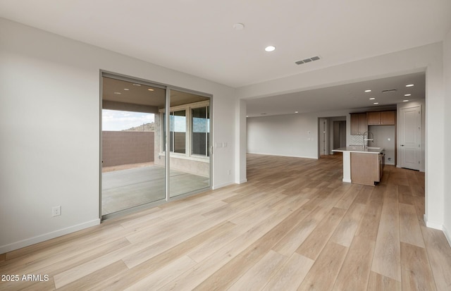 unfurnished living room featuring sink and light wood-type flooring