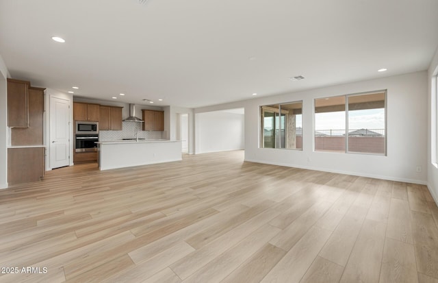 unfurnished living room with sink and light hardwood / wood-style floors