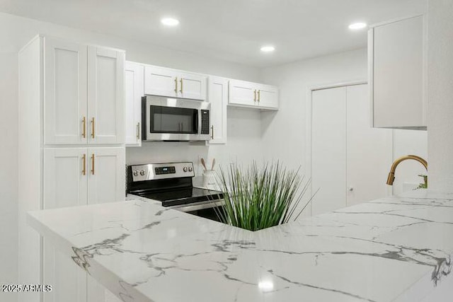 kitchen featuring white cabinetry, light stone counters, and appliances with stainless steel finishes