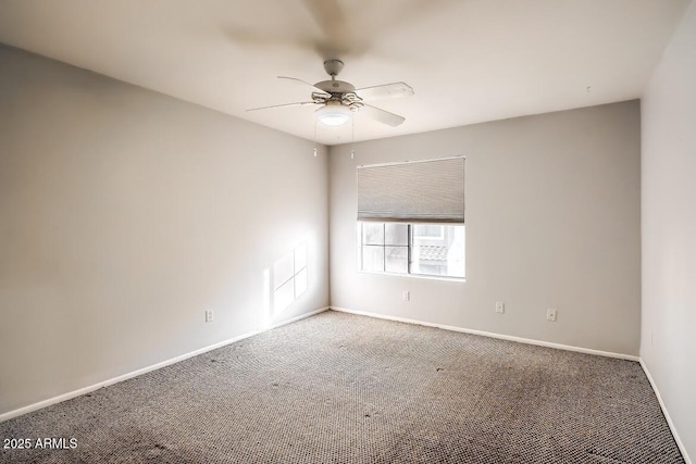 carpeted spare room featuring ceiling fan and baseboards