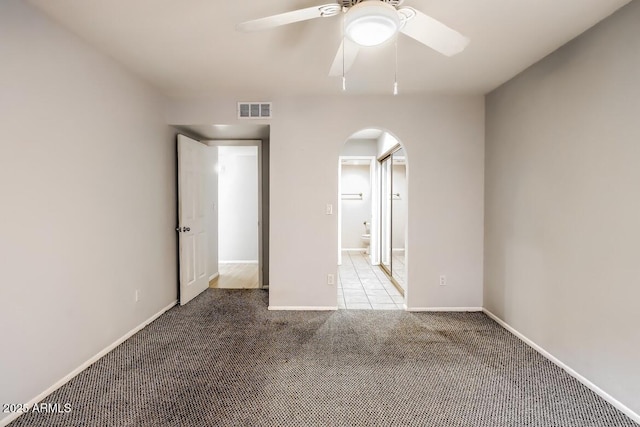 unfurnished bedroom featuring visible vents, arched walkways, baseboards, ensuite bath, and carpet