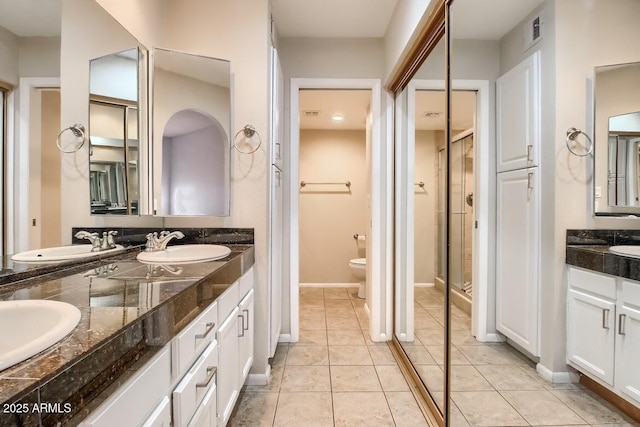 bathroom with toilet, double vanity, visible vents, and a sink