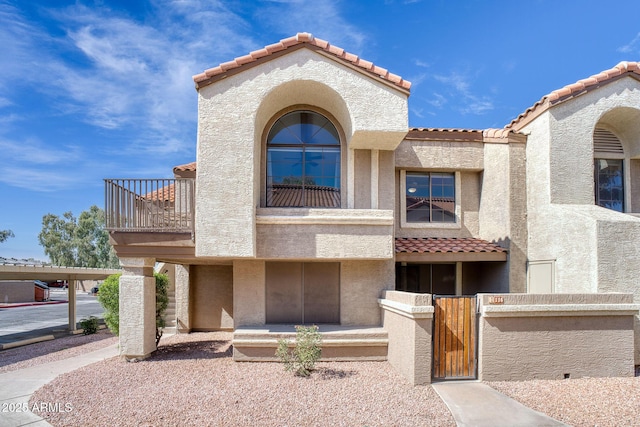 view of front of home featuring a balcony, a gate, and stucco siding