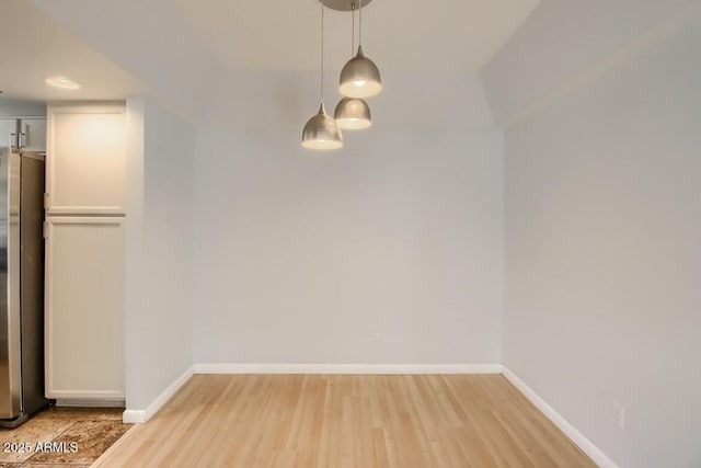 unfurnished dining area featuring light wood-style flooring and baseboards