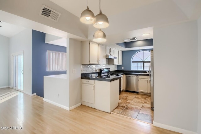 kitchen with appliances with stainless steel finishes, dark countertops, visible vents, and tasteful backsplash