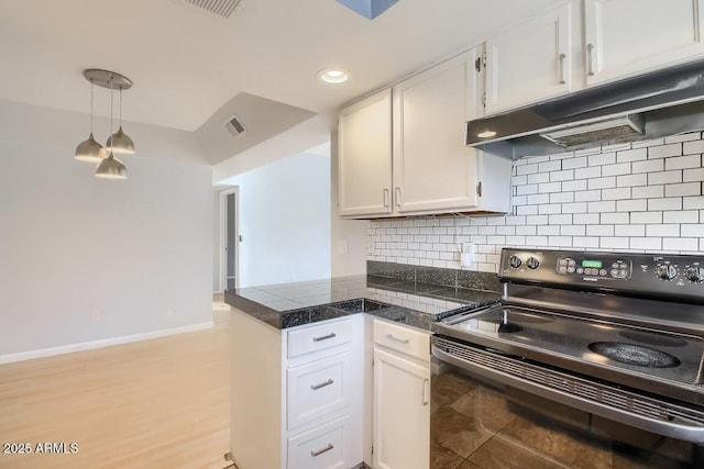 kitchen featuring tile counters, visible vents, black electric range oven, a peninsula, and under cabinet range hood