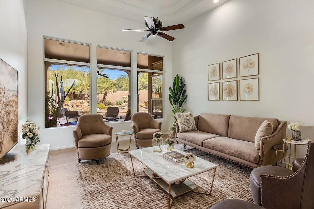 living room featuring a high ceiling, baseboards, and a ceiling fan