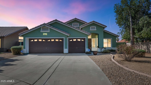 5153 W Topeka Dr, Glendale, AZ 85308 - view of front of house featuring a garage, driveway, a tiled roof, and stucco siding