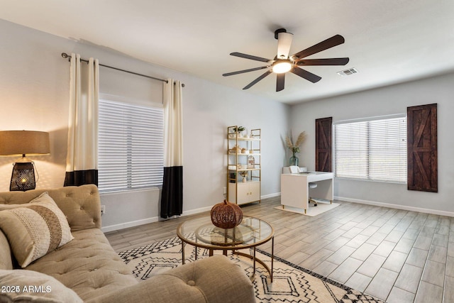 living area with ceiling fan, wood finished floors, visible vents, and baseboards