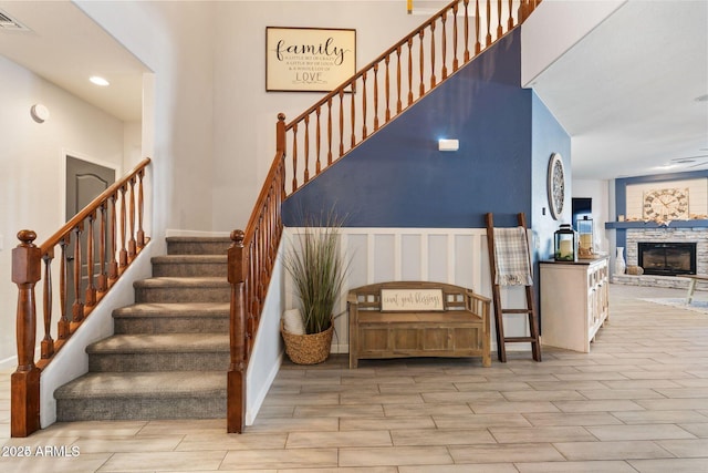 stairway with wood finish floors, visible vents, a fireplace, and baseboards