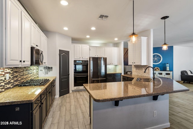 kitchen featuring dobule oven black, gas stovetop, a sink, freestanding refrigerator, and stainless steel microwave