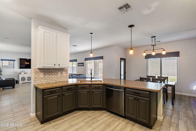 kitchen featuring tasteful backsplash, visible vents, white cabinets, a sink, and dishwasher