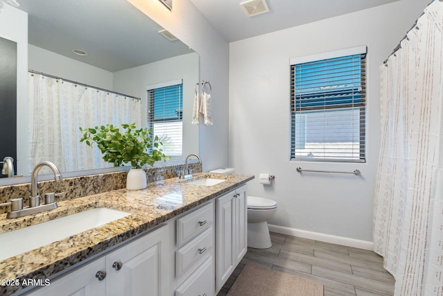 bathroom with visible vents, a sink, toilet, and double vanity